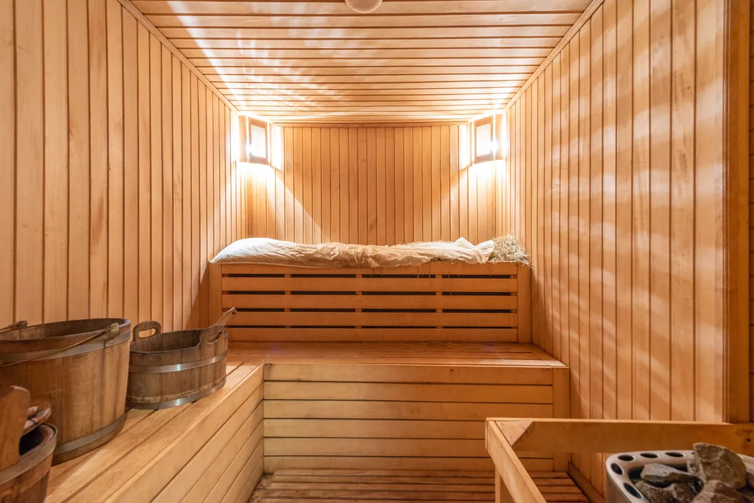 A warm wooden sauna with benches and soft wall lamps