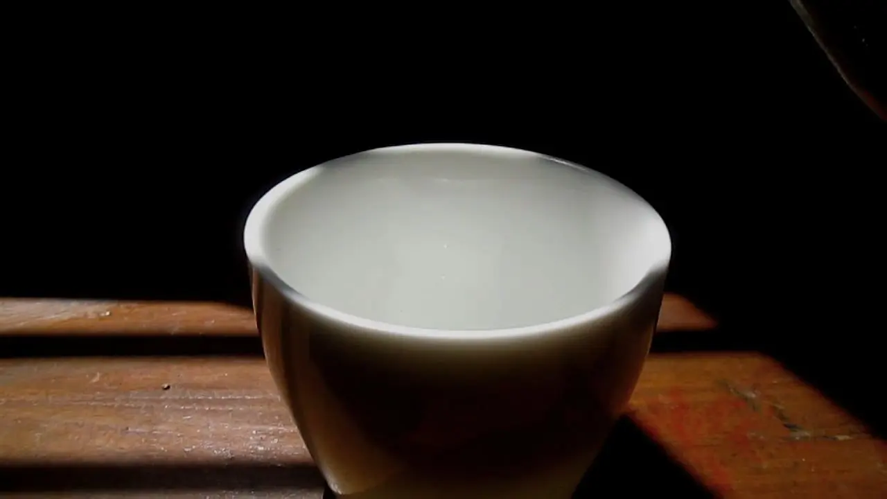 A white porcelain cup on a sunlit wooden counter, about to be filled