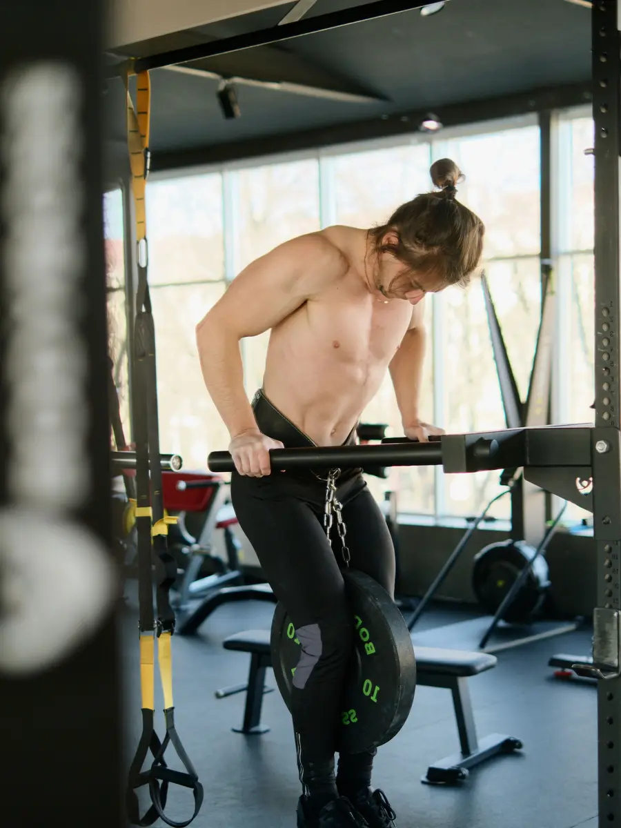 A man doing dips on parallel bars beside a bright window