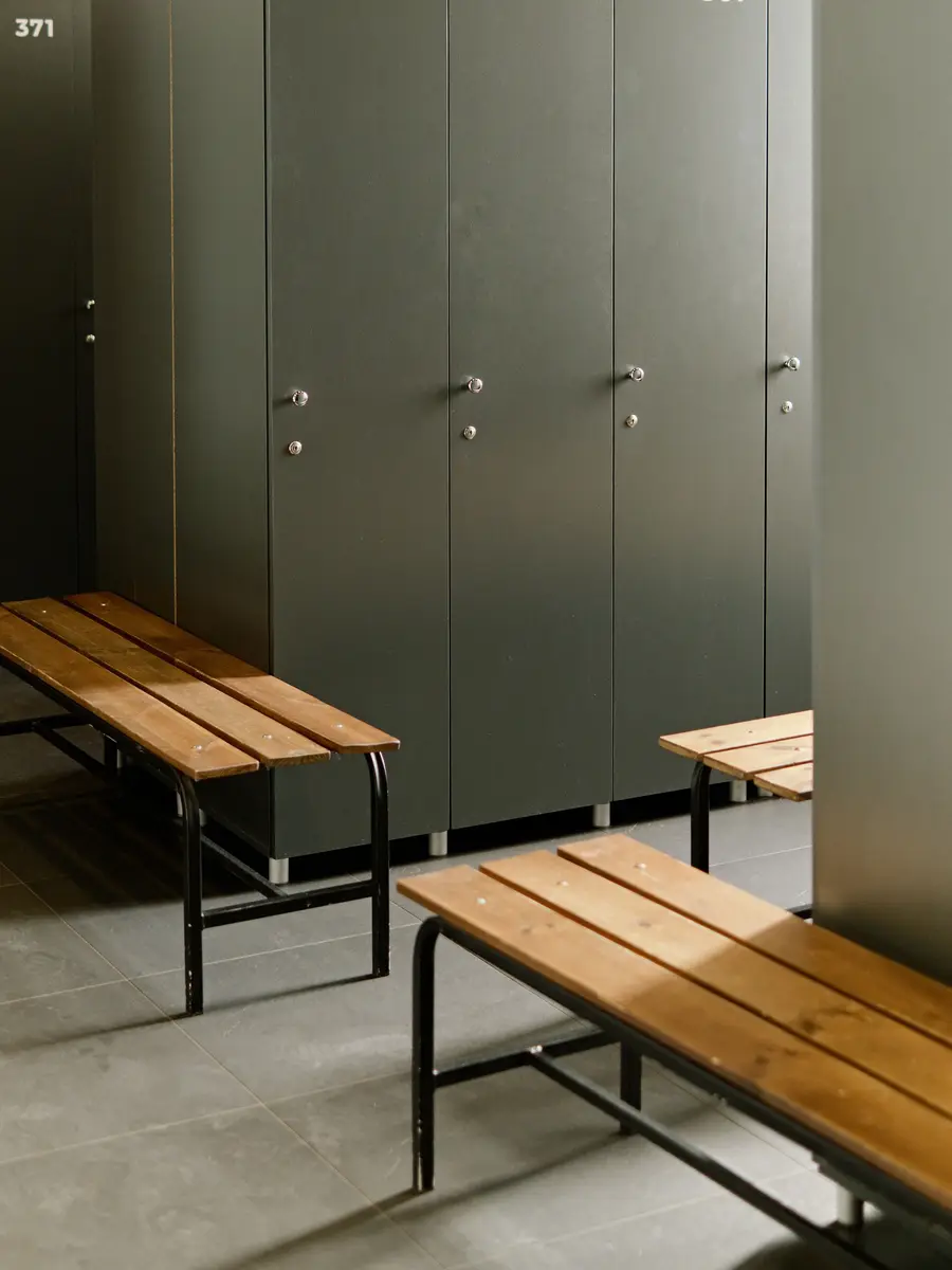 Sage-green lockers above two wooden benches in a quiet changing room