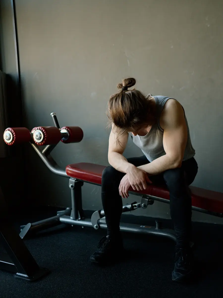 A woman resting on a bench between sets, head down