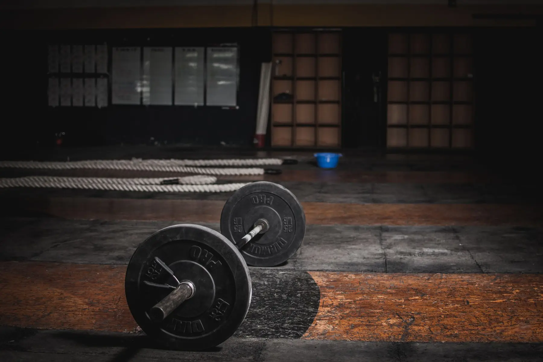 Loaded barbells resting on a worn wooden lifting platform in a dark gym