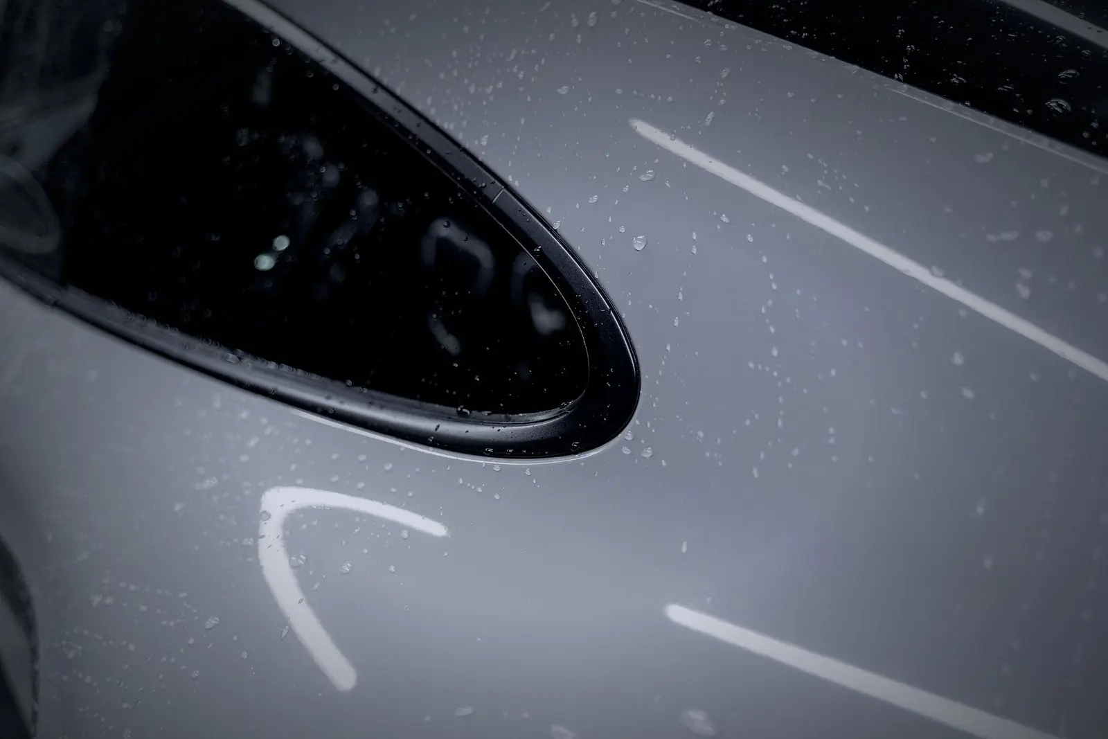 Raindrops on the grey flank and rear window of a sports car