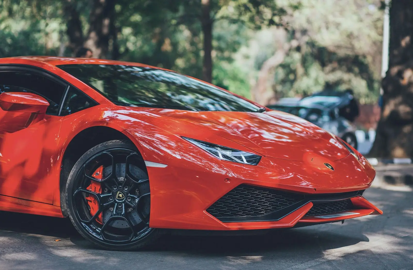 The front wheel and red brake caliper of a red supercar