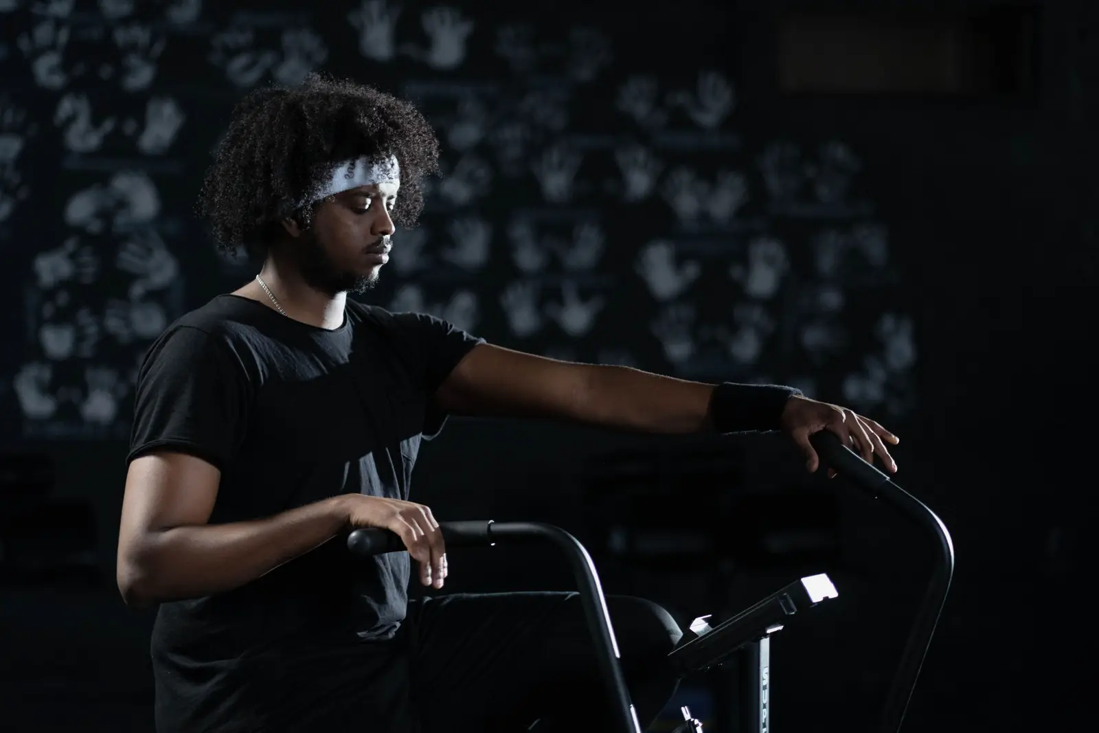 A woman in a headband pushing hard on an air bike