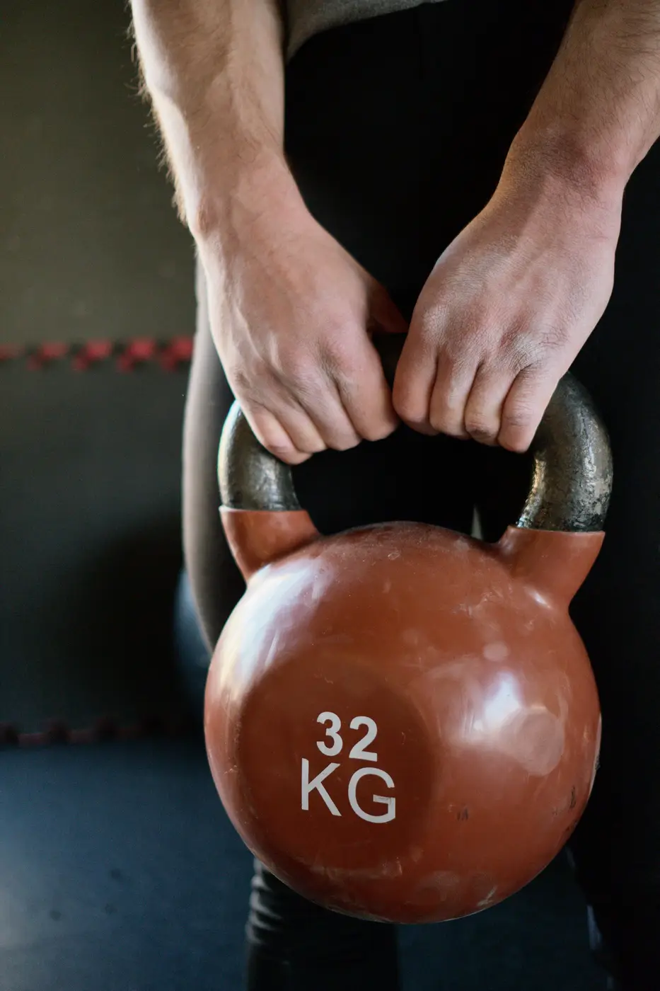 Close-up of two hands gripping a 32 kg kettlebell
