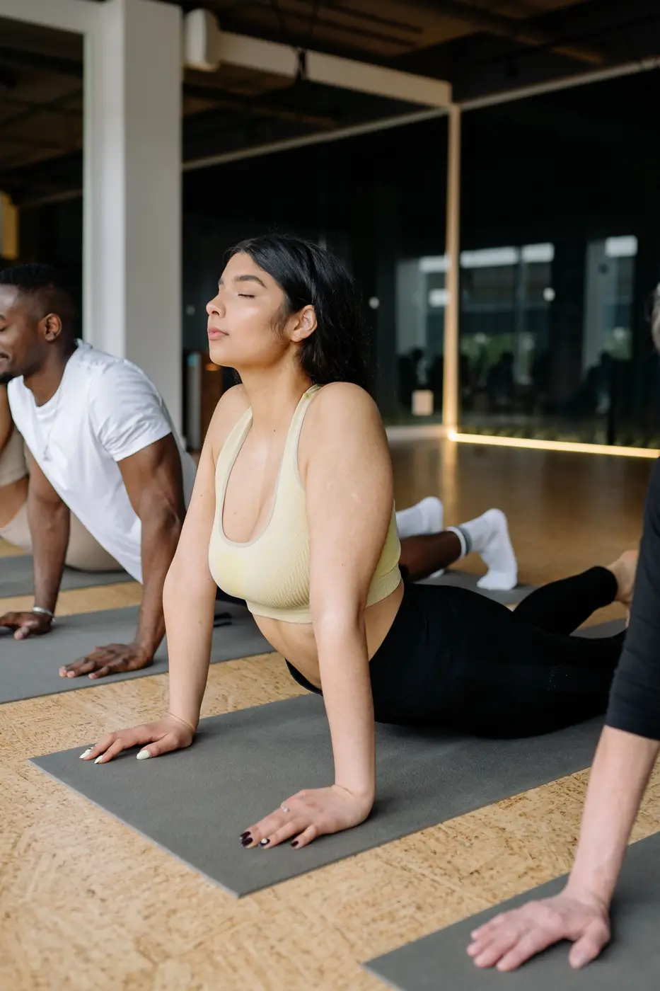 A woman in a cobra stretch on a mat, others behind her