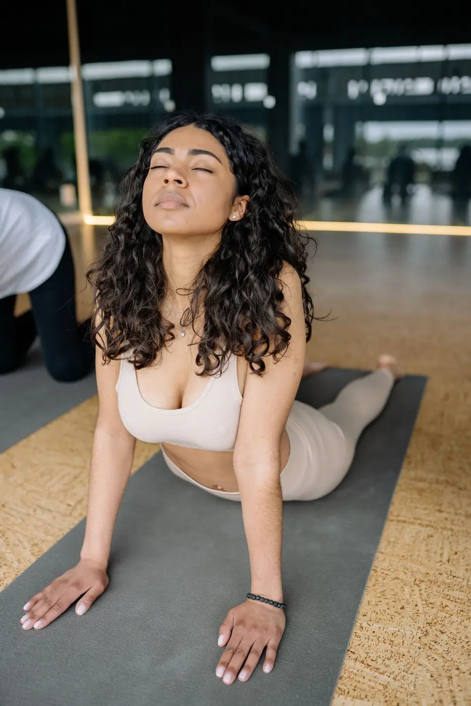 A woman stretching on a mat with her eyes closed