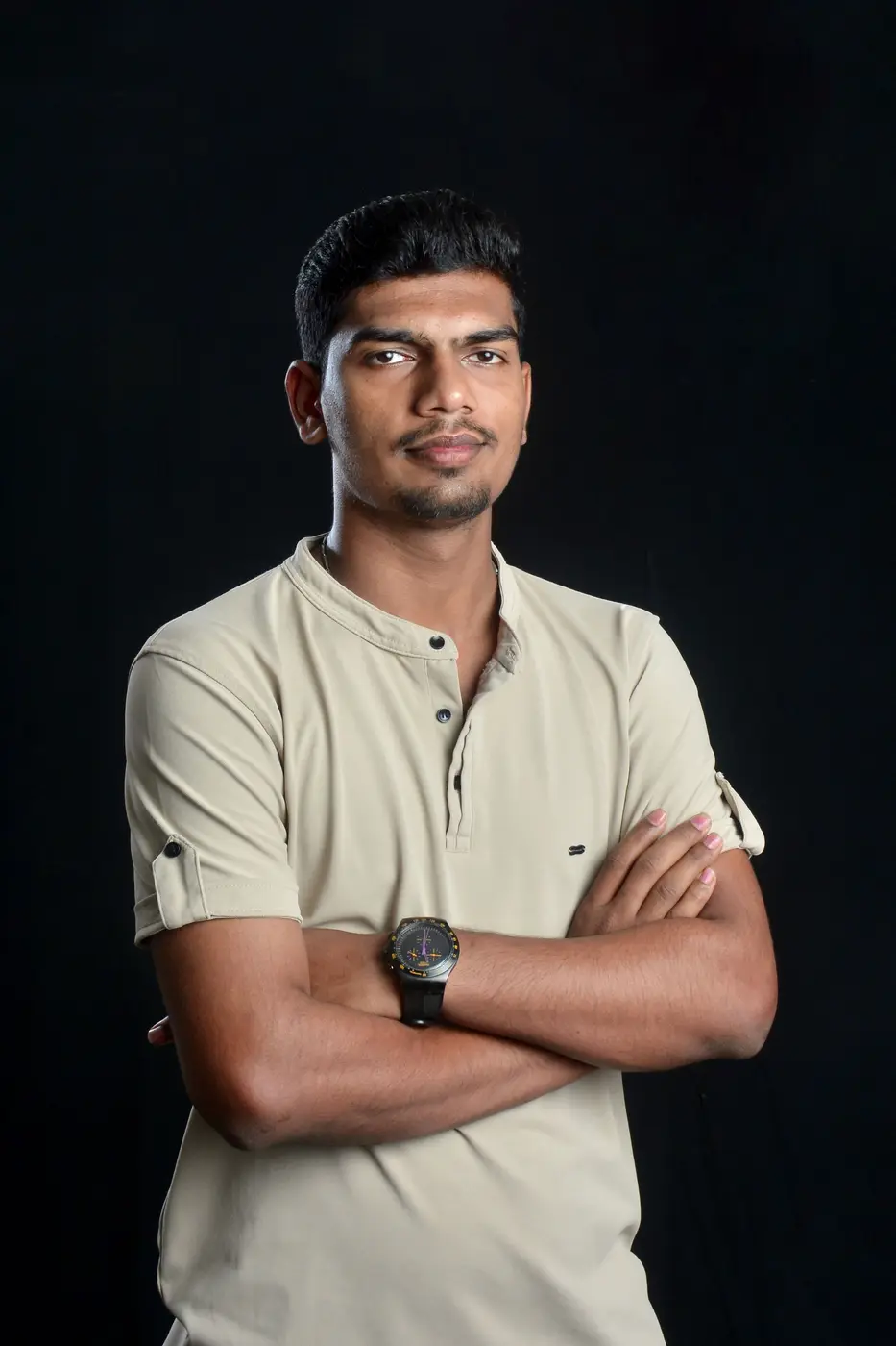 A coach in a pale polo shirt with folded arms against a dark background