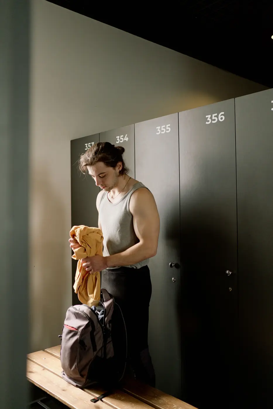 A man with a towel at his locker in a changing room